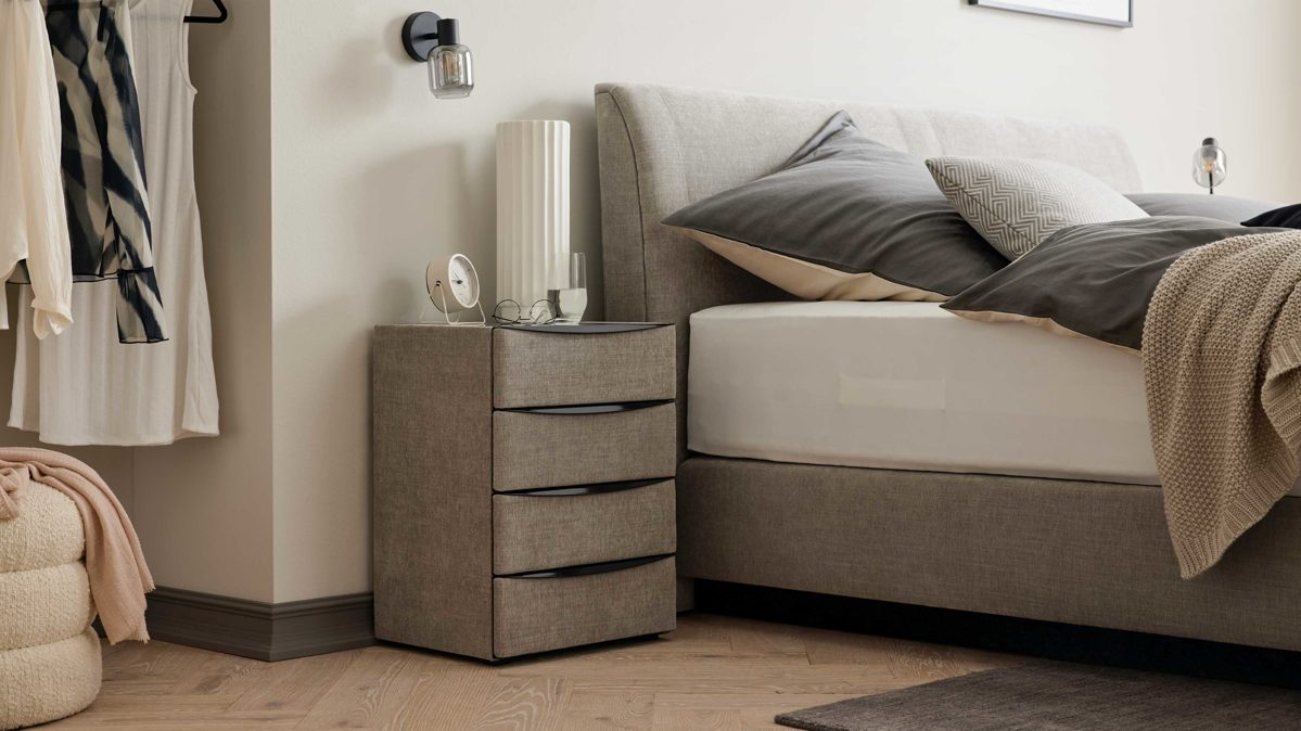 Nachtkommode Interliving aus Holz in Grau Interliving Boxspringbett Serie 1401 – Nachtkommode 64 silberfarbener Stoffbezug Rob 533006 – vier Schubladen