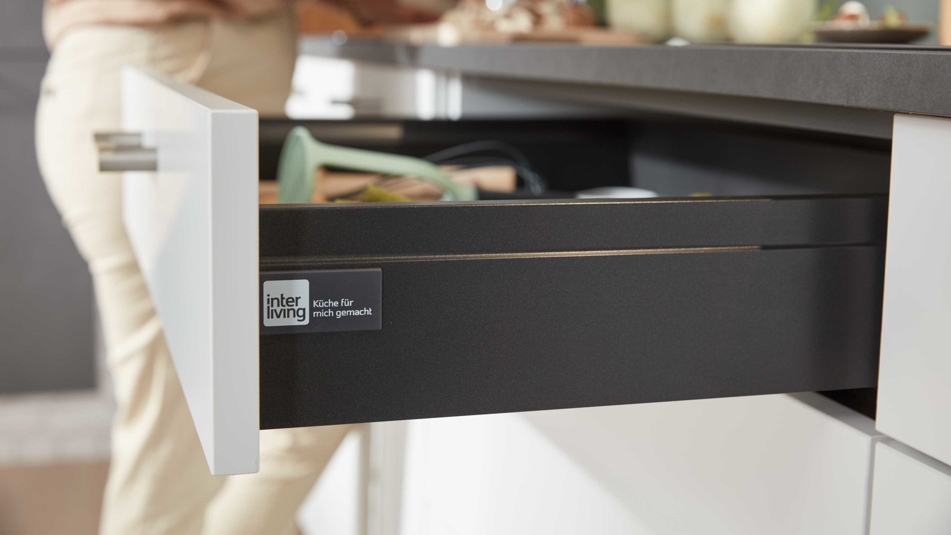 Einbauküche Interliving aus Holz in Grau Interliving Küche Serie 3019 mit AEG Einbaugeräten Weiß & Stahlgrau – zweizeilig