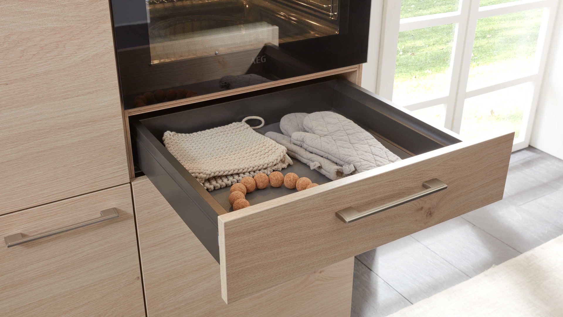 Einbauküche Interliving aus Holz in Holzfarben Interliving Küche Serie 3008 mit AEG Einbaugeräten Stahlgrau & Asteiche – zweizeilig