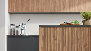 Einbauküche Interliving aus Holz in Schwarz Interliving Küche Serie 3076 mit Miele-Einbaugeräten Mattschwarz & Stripe Wood Choco - dreizeilig