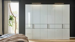 Möbelbeleuchtung Interliving aus Holz in Weiß Interliving Schlafzimmer Serie 1033 – Kleiderschrank 605 mit Beleuchtung weißes Glas & Holz – sechs Türen, Breite ca. 300 cm